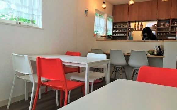 カフェグリーンの真っ白なテーブルと紅白のイスが置かれた明るい店内