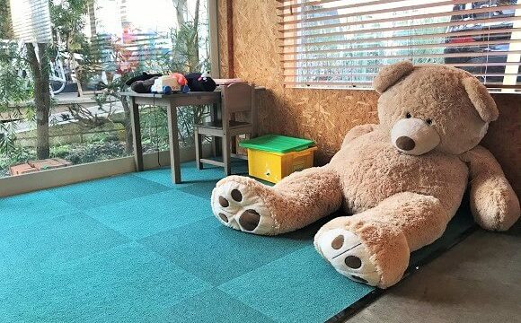 『コイガクボ』の子供用プレイスペースに置かれた大きなクマのぬいぐるみ